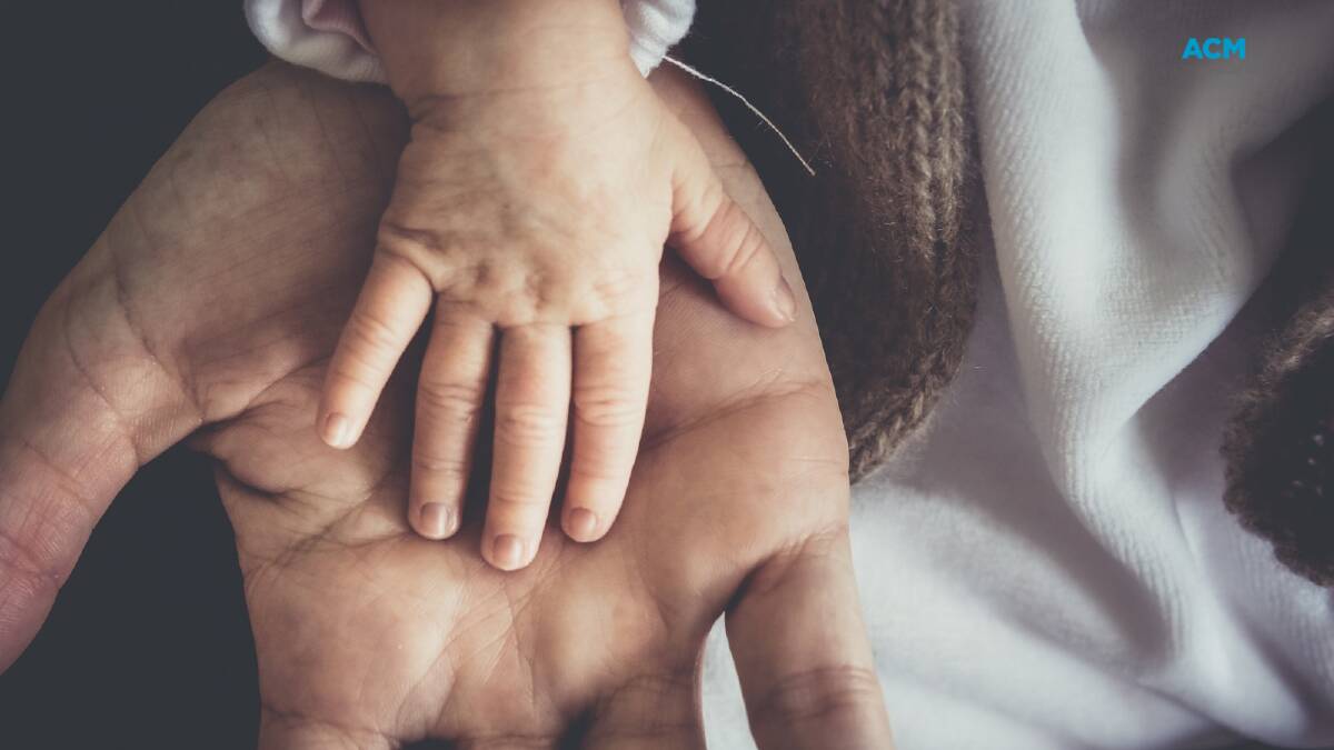 A child's hand rests on an adult's hand. Picture via Canva