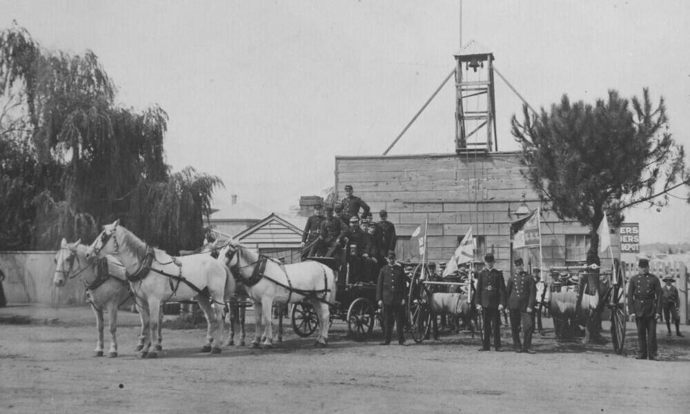 Orange Fire Brigade outside the first Fire Station in Anson Street in about 1900. Several men are seated on an engine drawn by four horses; others are standing beside two firehoses mounted on wheels. This image appears in the publication Celebrating Orange. Picture from Central West Libraries